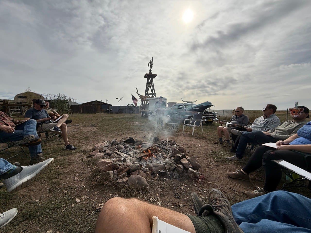 Corporate retreat group gathered around the fire pit at the Cadillac Wanch with the windmill and Cadillac in the background