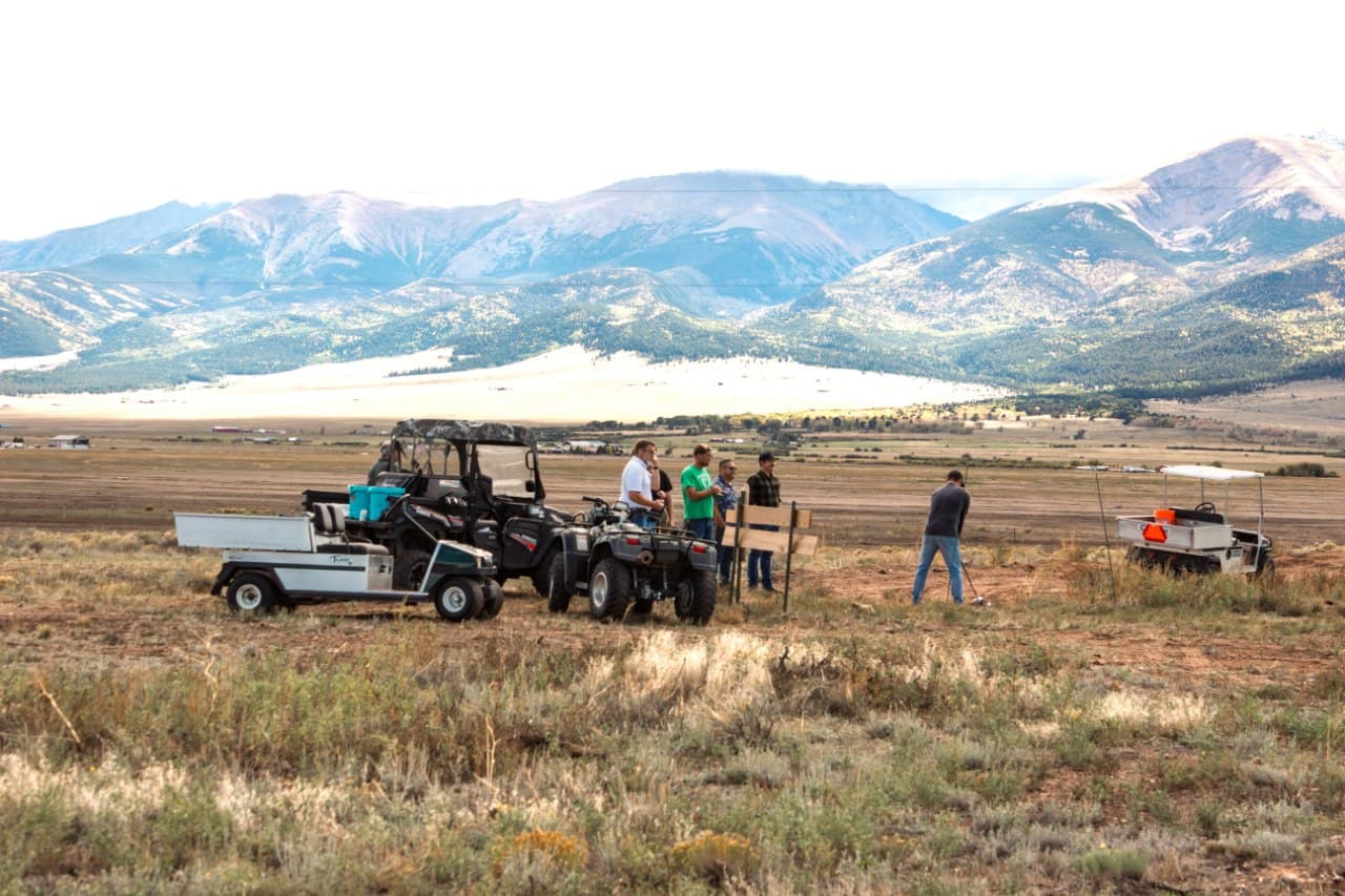 Build day — the crew gathered at a tee box marker with the Sangre de Cristo range behind