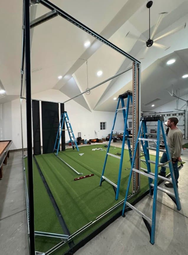 Steel bay frame going up — ladders show scale against the vaulted ceiling.
