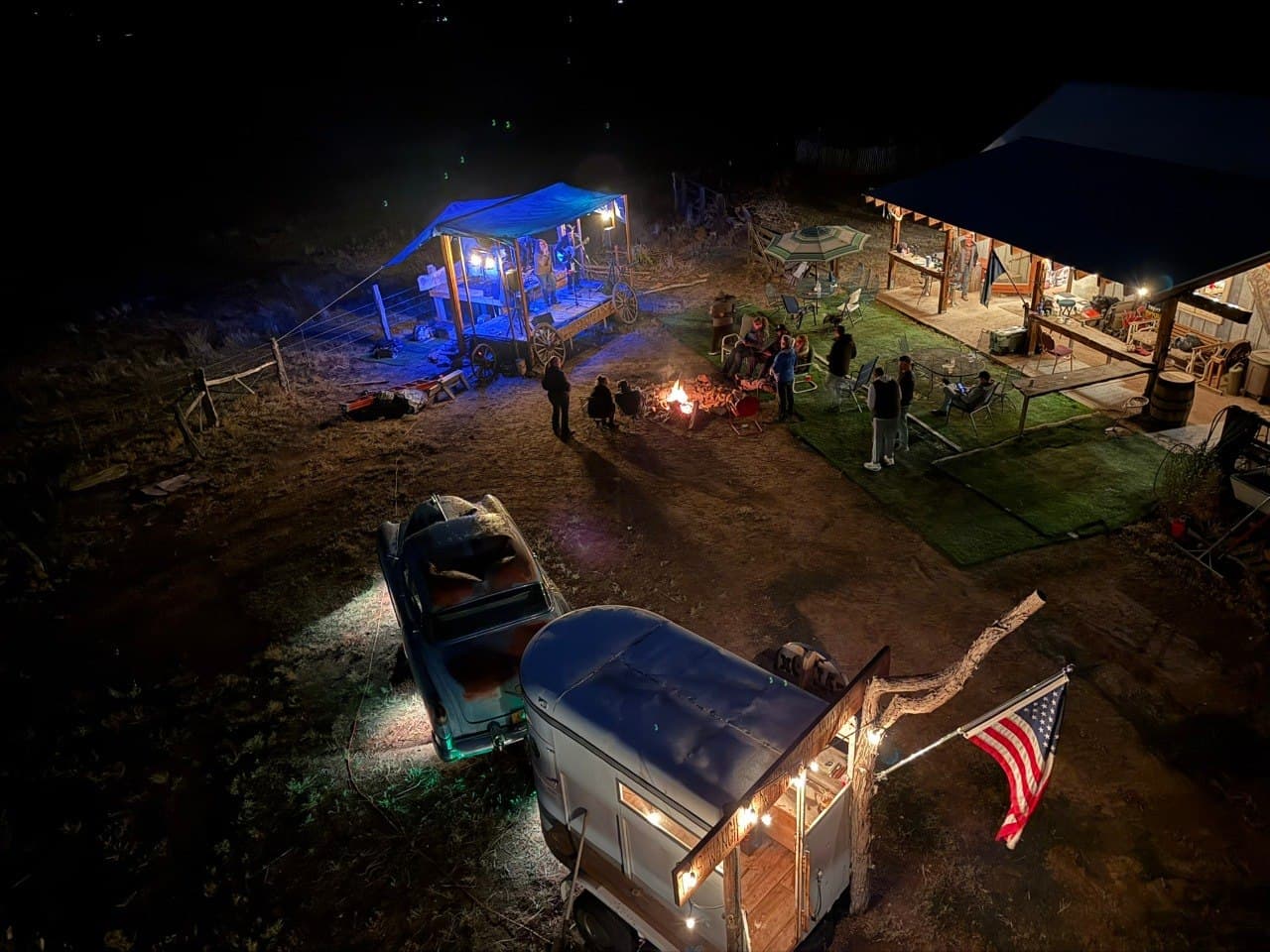 View from atop the windmill of the MVWD corporate retreat at the Cadillac Wanch — live music stage, fire pit gathering, vintage truck, and American flag at night