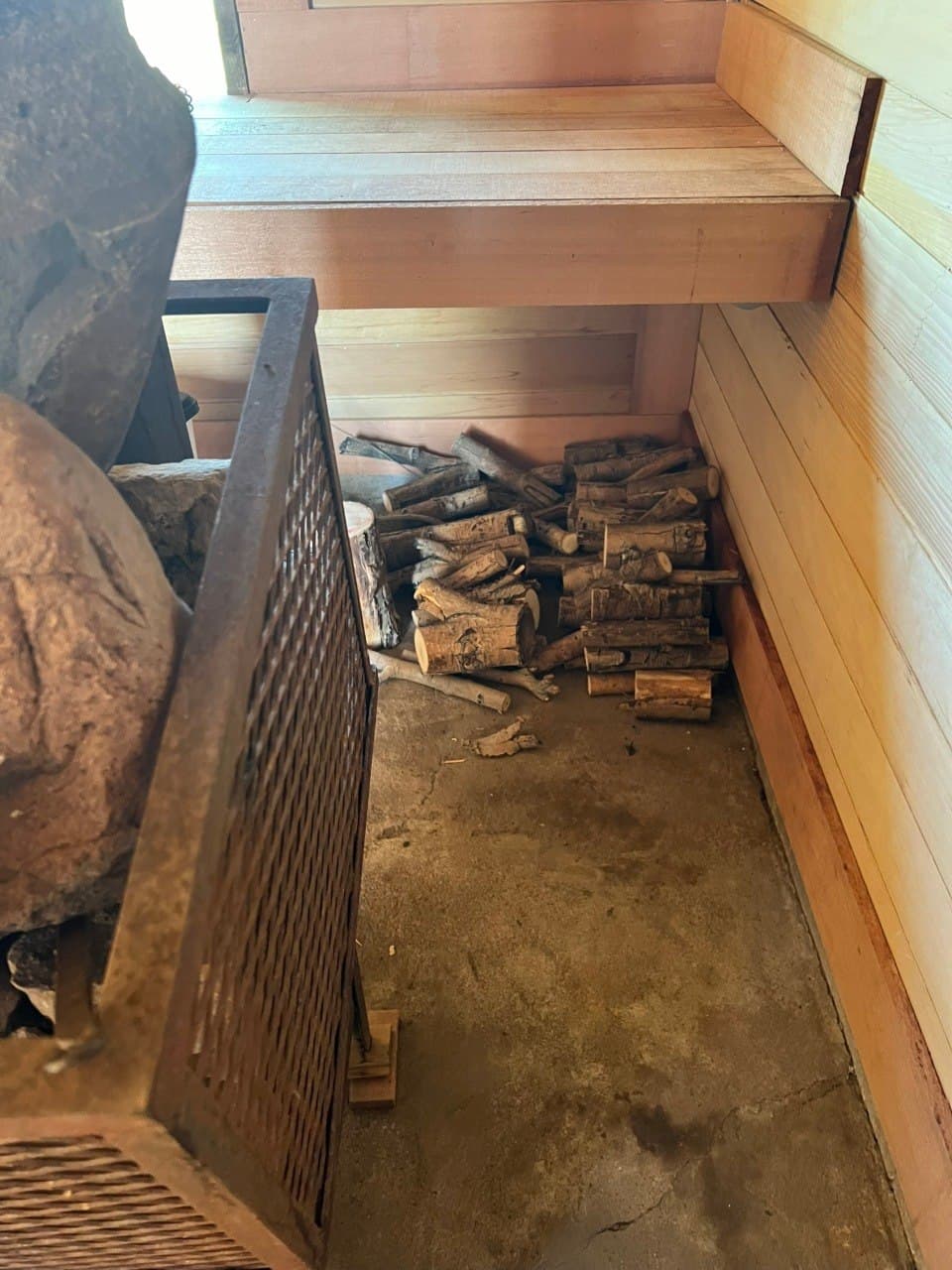 Inside the sauna — wood-fired stove with stacked firewood and heated rocks