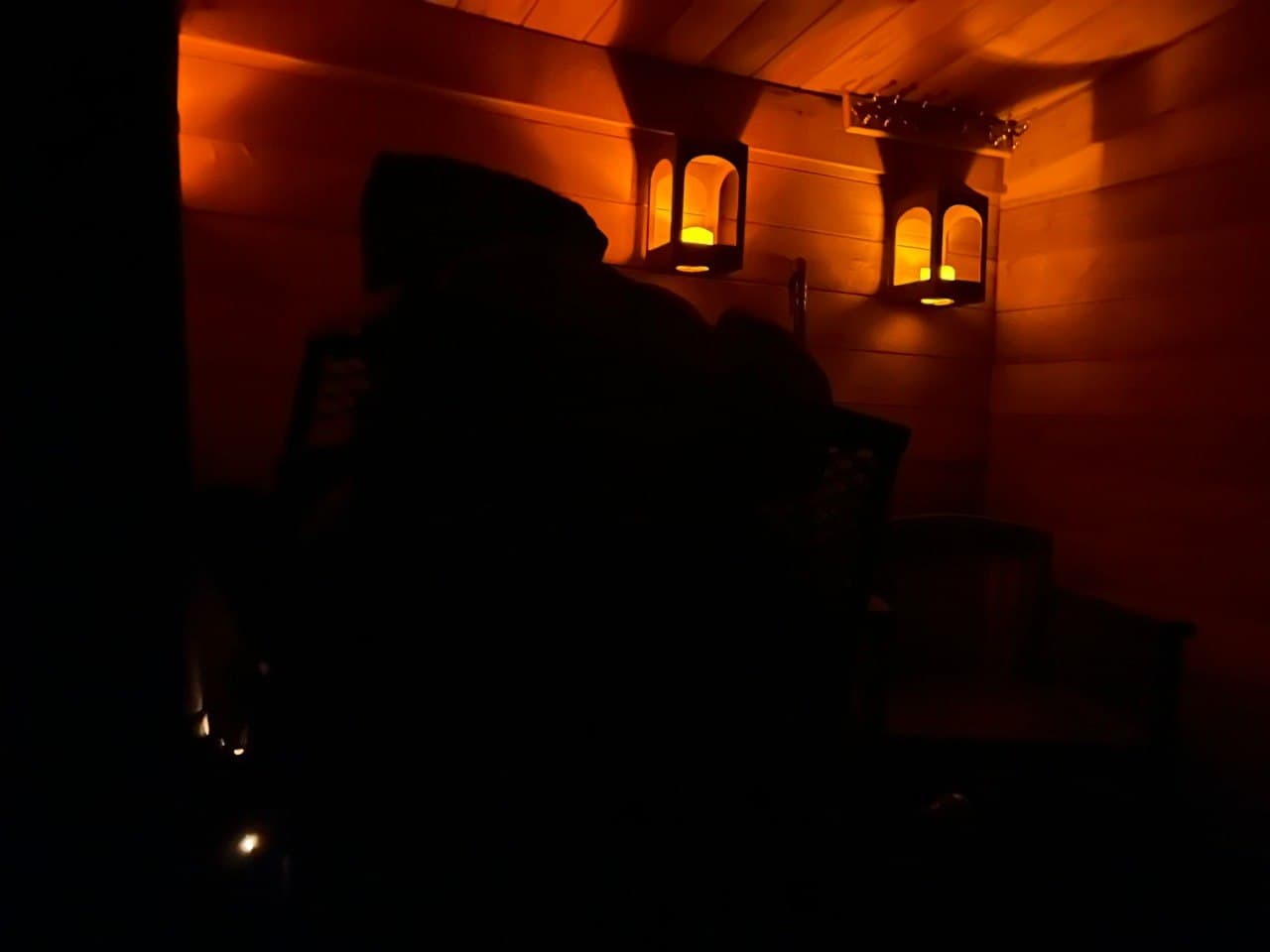 Sauna lit by lantern glow at night — warm cedar walls and amber light for an evening session