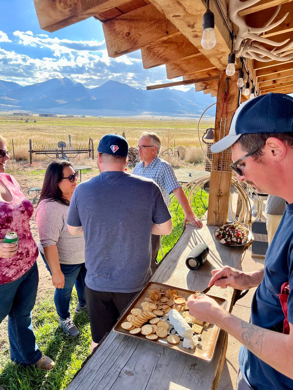 Retreat arrivals under the homestead porch — cheese board, Sangres view